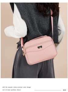 Detail view of the pink PU leather cross-body bag showing metal zipper and brand badge.