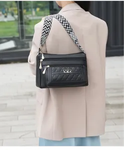 Stylish black leather multi-pocket shoulder crossbody bag with wide geometric strap detail.