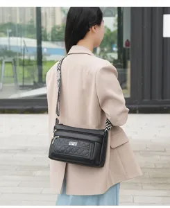 Detailed view of women's black quilted crossbody bag with patterned strap outdoor street shot.