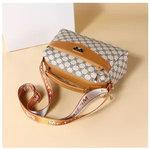 Bolso bandolera vintage con monograma, ribetes de cuero marrón y correa de lona ancha.