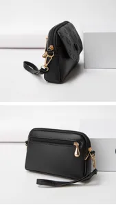 Black mini crossbody bag detail view showing gold hardware, zipper pocket and wrist strap.
