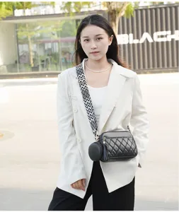 Close-up detail of women's black quilted crossbody bag featuring wide strap and cute pouch.
