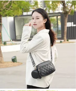 Detailed view of women's black quilted crossbody bag with wide strap and chic tassel.