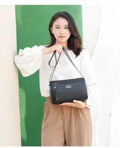 Close-up detail of the stylish black commuter crossbody bag with trendy tassel and strap.