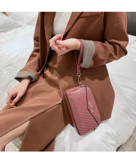 Detail view of stylish pink mini women leather handbag clutch with cute bow and wrist strap.