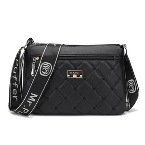 Sac bandoulière matelassé noir pour femme avec sangle large griffée et badge en métal.