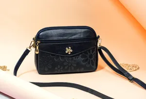 Detailed view of the dark blue crossbody bag, showcasing floral embossing and gold hardware details.
