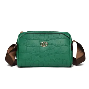 Detailed view of green crocodile textured leather crossbody bag with brown strap and metal logo.