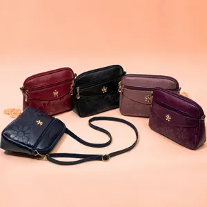 Detailed view of women's PU leather crossbody bag with floral embossing and metal decor.