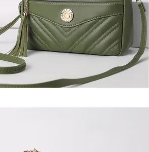 Close-up detail of green soft leather crossbody bag with chevron quilting and chic tassel accent.