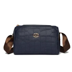 Detailed view of the dark blue crossbody bag with crocodile texture and metal Mr logo.