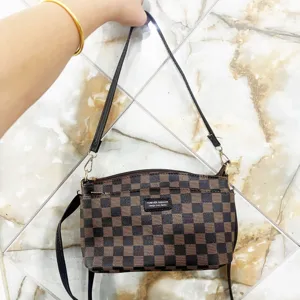 Detailed view of brown checkerboard shoulder bag with black strap and metallic hardware accents.