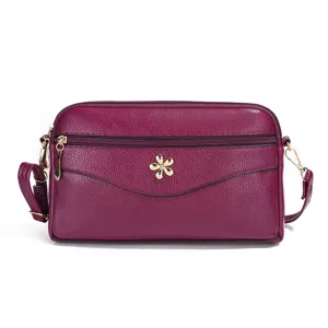 Purple leather crossbody bag with multiple zipper compartments, metal flower decor detail.