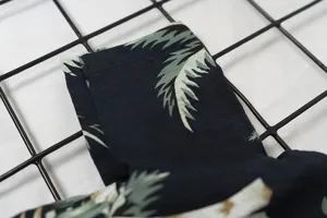 Detailed view of summer tropical leaf print pet shirt fabric, lightweight breathable clothing.