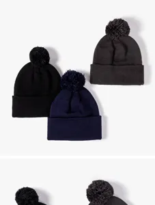 Detailed view of winter knitted beanie hats with fluffy pom poms, cozy warm wool caps.