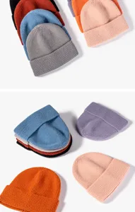 Close-up detail of soft knit winter beanies in vibrant assorted colors. Textured cozy fabric.