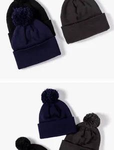 Close-up detail shot of warm winter knitted pom-pom beanies in classic solid colors.