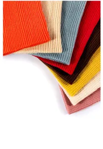 Close up view of colorful ribbed knit beanie stacked neatly, showing soft winter texture.