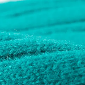 Bright turquoise knitted beanie close-up showing soft textured wool fabric details.