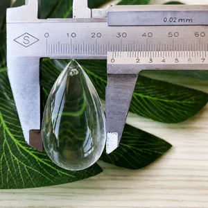 Clear glass teardrop pendant detail showing dimensions and measurement with a caliper.