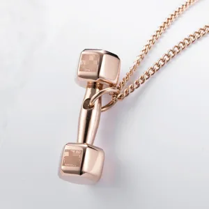Détail de collier pendentif haltère en or rose exquis, bijoux fitness en acier.