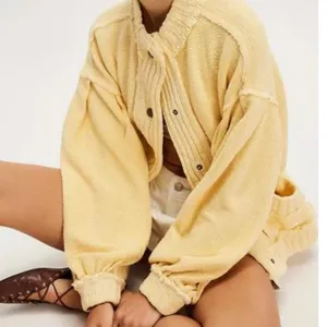 Detailed view of yellow vintage distressed knit cardigan with snap buttons and rib collar.