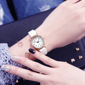 Gros plan détail de montre quartz femme avec cadran blanc, bracelet en cuir et main délicate.
