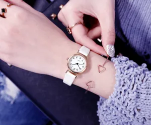 Gros plan de montre quartz femme minimaliste, petit cadran blanc et bracelet cuir.