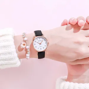 Wrist detail of minimalist quartz watch with black leather strap and floral bracelet.