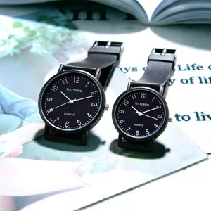 Close-up detail of black dial minimalist quartz couple watches with clear numbers and straps.