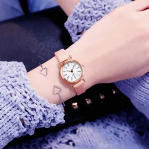 Gros plan détail d'une montre quartz pour femme avec bracelet en cuir rose et cadran épuré.
