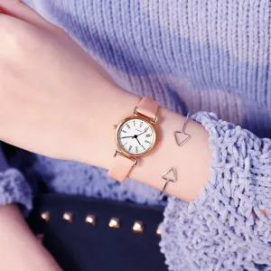 Gros plan détaillé de la montre à quartz à cadran rose et bracelet en cuir portée au poignet.