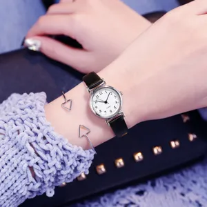Close-up detail of vintage small dial quartz watch with black leather strap on wrist.