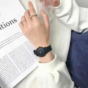 Gros plan détaillé d'une montre bracelet à cadran noir minimaliste avec bagues élégantes.