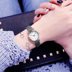 Detail shot of a vintage mini green leather strap quartz watch with white dial and cuffs.