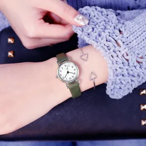 Close-up view of minimalist green leather strap quartz watch with small dial and bracelet.