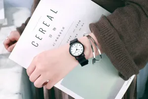 Detail shot of a minimalist black quartz watch paired with sleek silver bangles on a wrist.