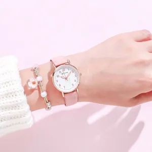 Close-up of a cute pink leather strap watch with a white dial and beaded charm bracelet.