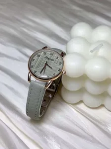 Detailed close-up view of minimalist womens watch featuring grey leather strap and textured dial.