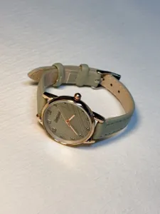 Close-up detail of women quartz watch featuring textured grey dial and pastel green strap.