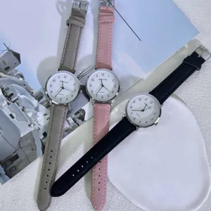 Minimalist quartz watch detail showing grey pink and black leather straps with clear dial.