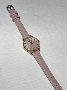 Detail view of the elegant pink leather strap quartz watch with rose gold dial and clear numbers.