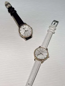 Detailed shot of minimalist women quartz watches with black and white leather straps, striped dials.