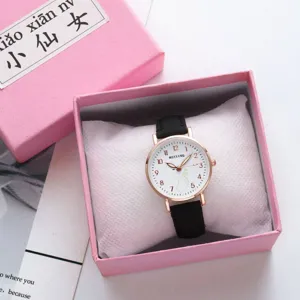 Minimalist quartz wrist watch detail with black strap and white dial in a pink gift box.
