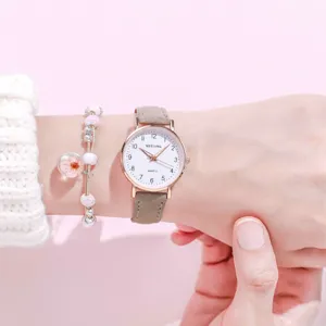 Close-up detail of women's quartz watch with minimalist white dial and brown leather strap.