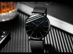 Minimalist men's quartz watch detail shot featuring black dial, blue markers and mesh strap.