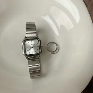 Minimalist square quartz watch with silver strap detail, elegant wrist accessory close-up.