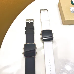 Digital electronic watch detail view featuring black and white silicone straps and screen display.