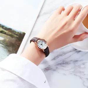 Close-up detail of women's vintage quartz watch with brown leather strap and small dial.
