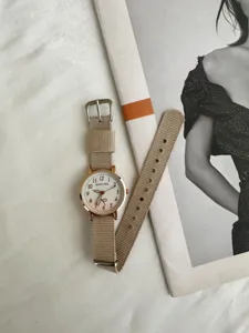 Minimalist canvas strap watch detail shot featuring a round rose gold case and clean dial.